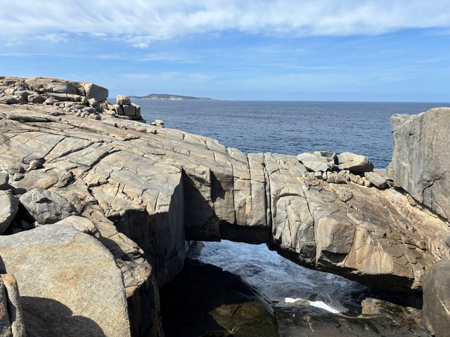 Rocky coastline with natural arch formation jutting into the sea.