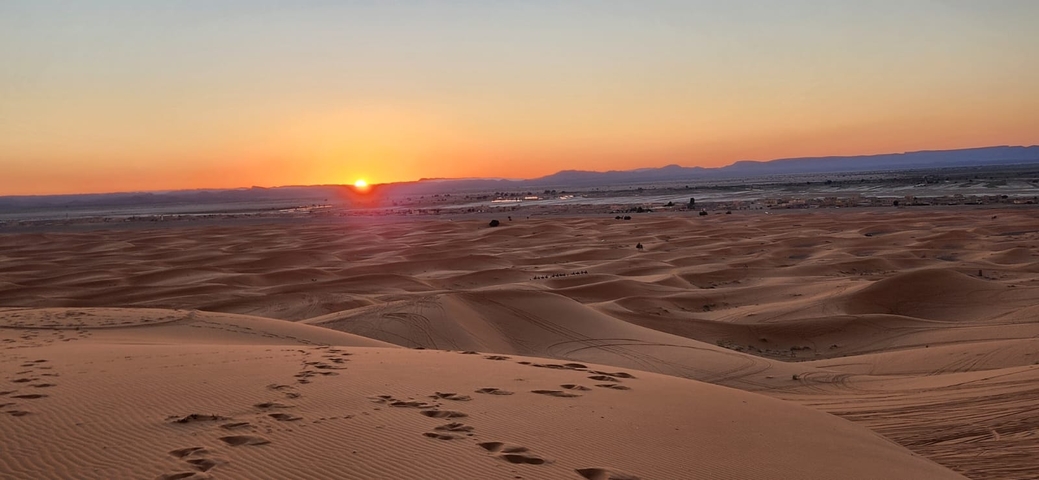 Sunset over vast sand dunes in the desert.