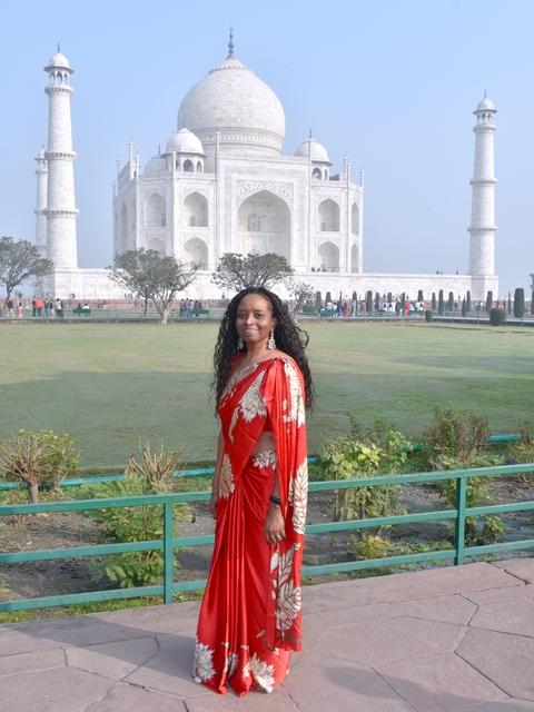 Woman in a saree with Taj Mahal in the background.
