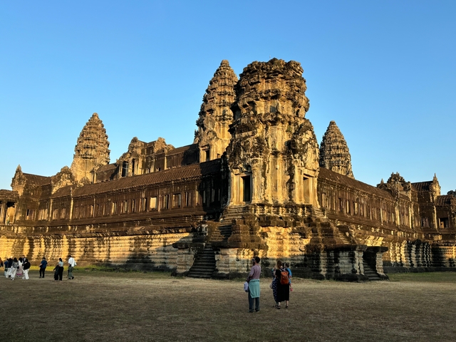 Ancient Angkor Wat temple with tourists walking around.