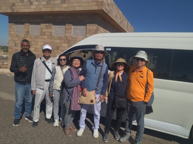 Group of people posing next to a white van.