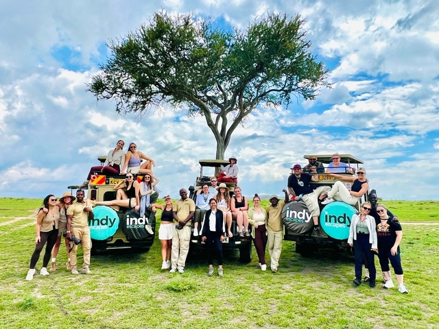       Group of people with safari vehicles in open savannah.
  