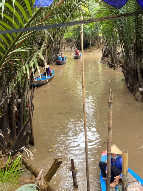 Narrow river channel with small boats among greenery.
