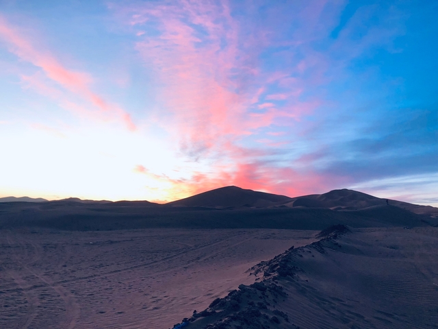 Beautiful sunset over desert dunes with colorful skies.
