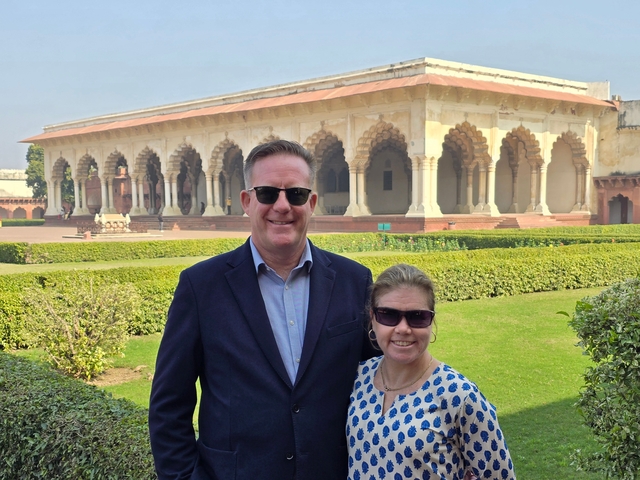 Couple posing in front of historic architecture with gardens.