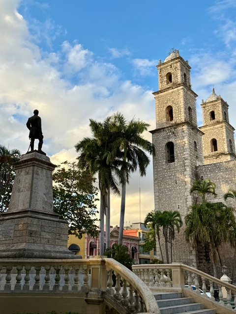 Historic statue and stone building in a tropical setting.
