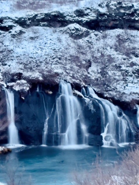 Blurry view of a waterfall surrounded by rocky terrain.
