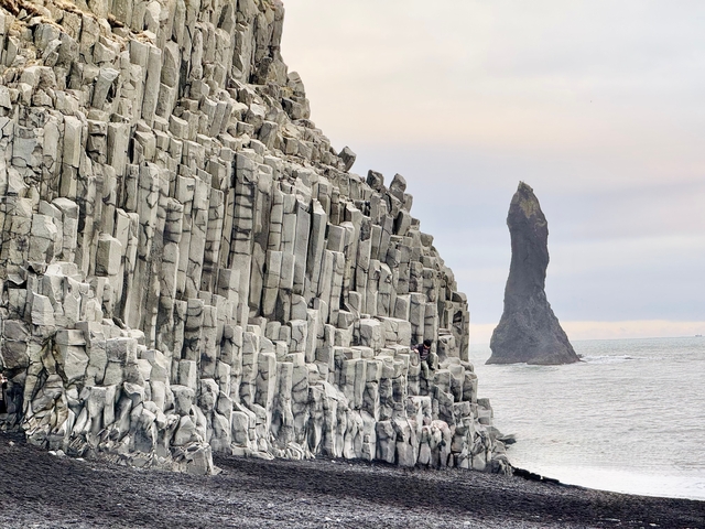 Rocky coastal landscape with basalt columns and an oceanic stack.