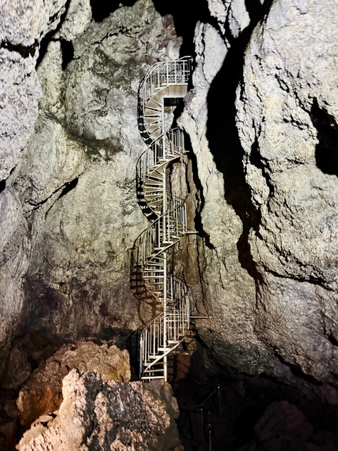 Metal spiral staircase inside a cave or rock formation.