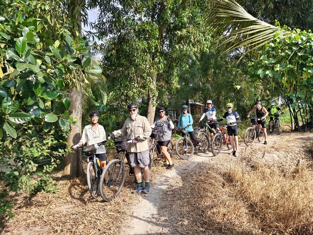 Cyclists resting along a path in a tropical setting.