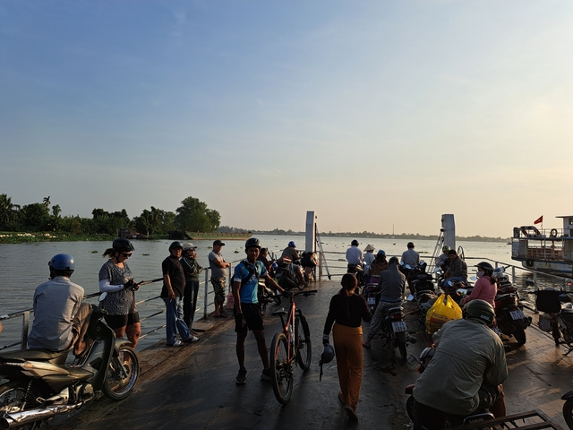 People on a ferry crossing a river with scooters.