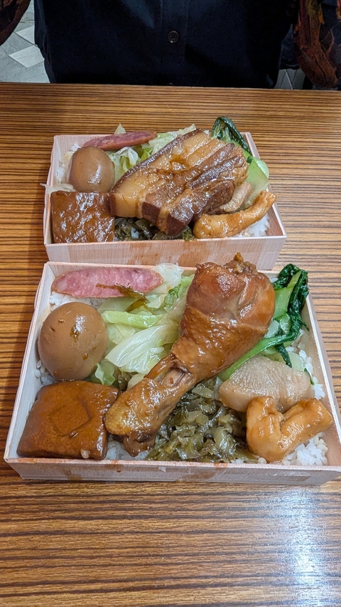       Boxed meal with various dishes on rice.
  
