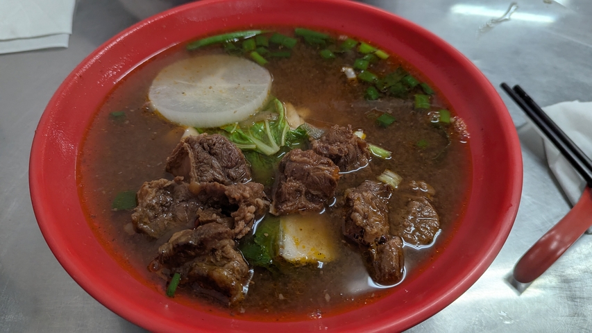      Bowl of noodle soup with beef slices.
  