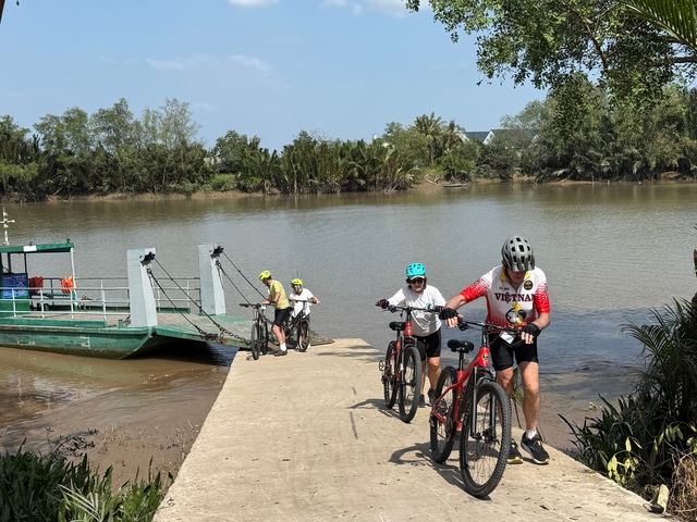 People with bicycles coming off a small ferry on a river.