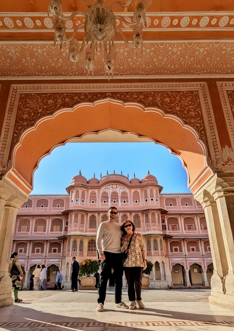 Couple posing under a grand archway in front of a palace.