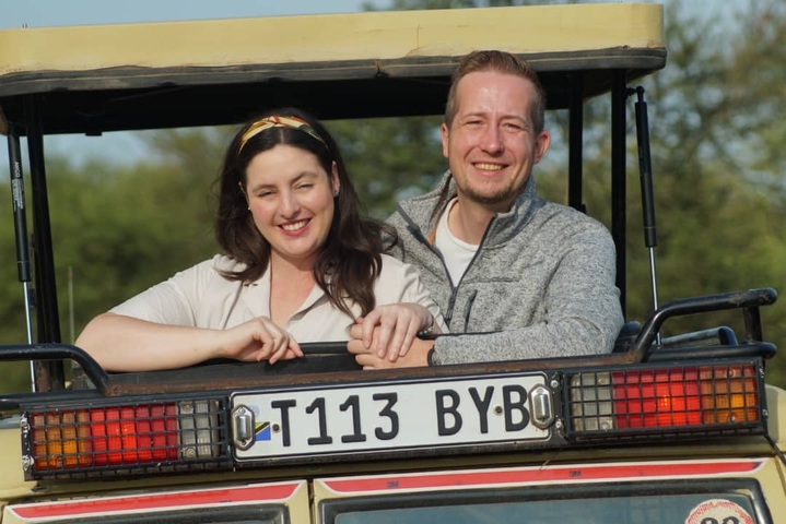       Close-up of two smiling people in a safari vehicle.
  