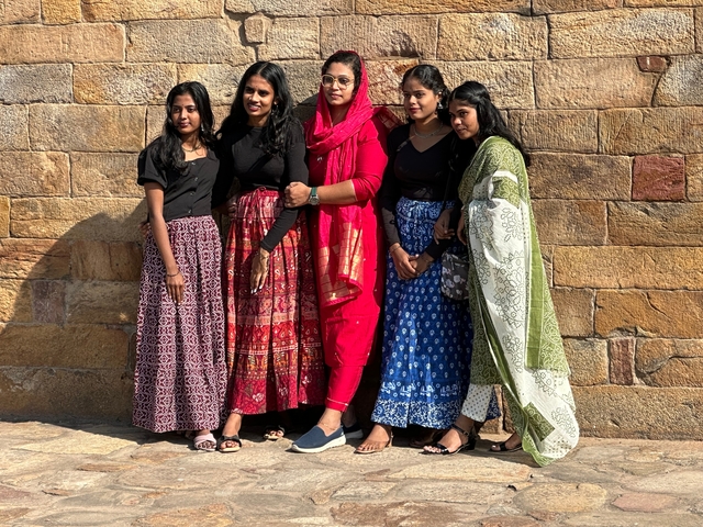 Group of women posing against a stone wall.