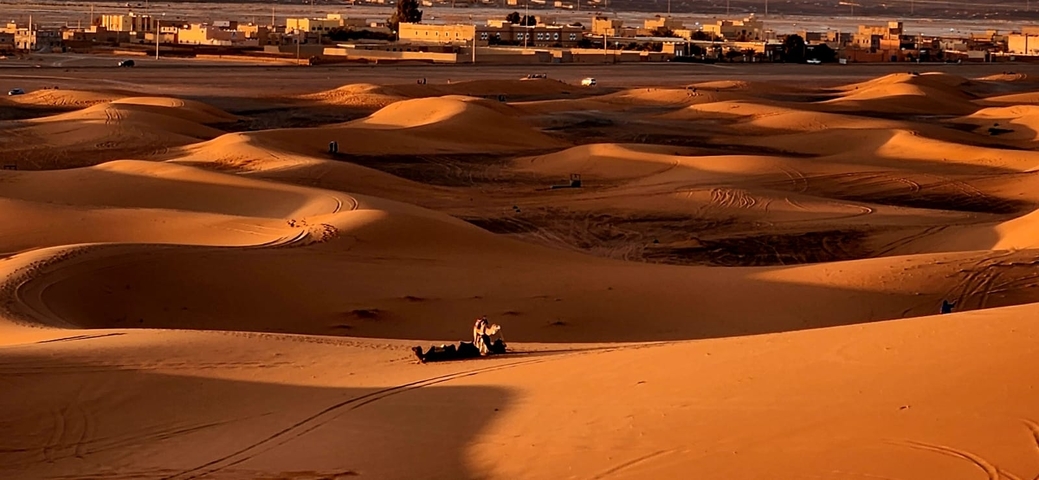 Desert dunes with a subtle orange glow at sunset.