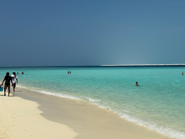       People enjoying a beautiful sandy beach with turquoise water.
  