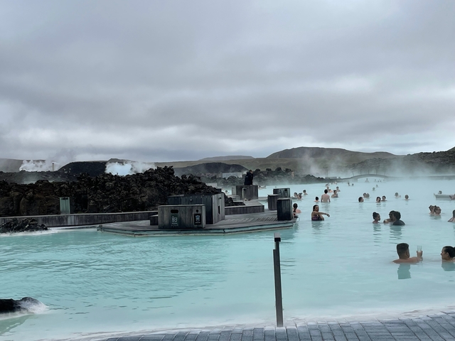       People relaxing in a geothermal spa with mountainous background.
  