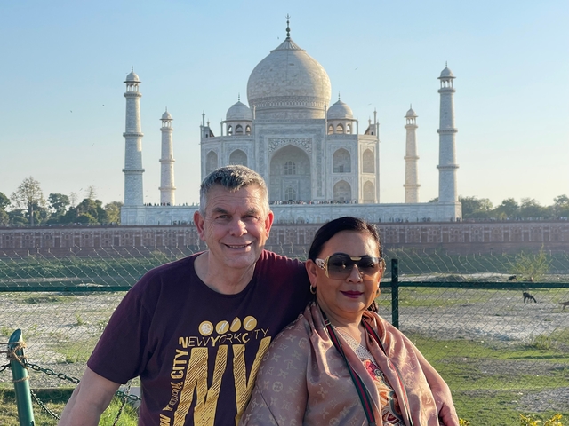       Couple posing in front of the picturesque Taj Mahal.
  