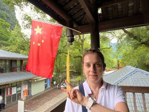 A person posing with a Chinese flag in a cultural setting.
