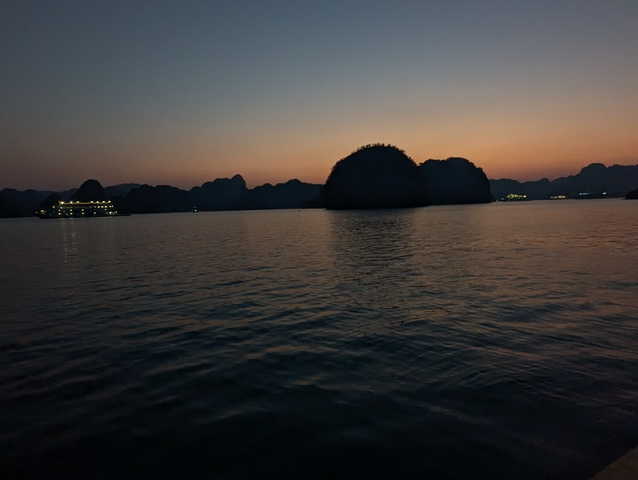       Silhouette of mountains at sunset over water.
  