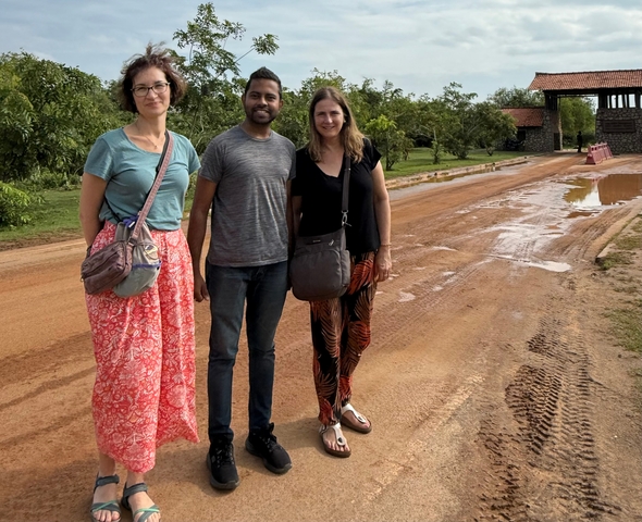 Three people standing on a muddy road.