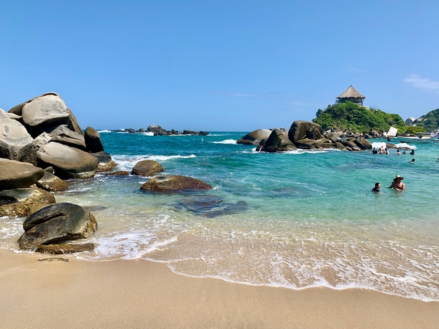 Beach with clear blue waters and rocks.