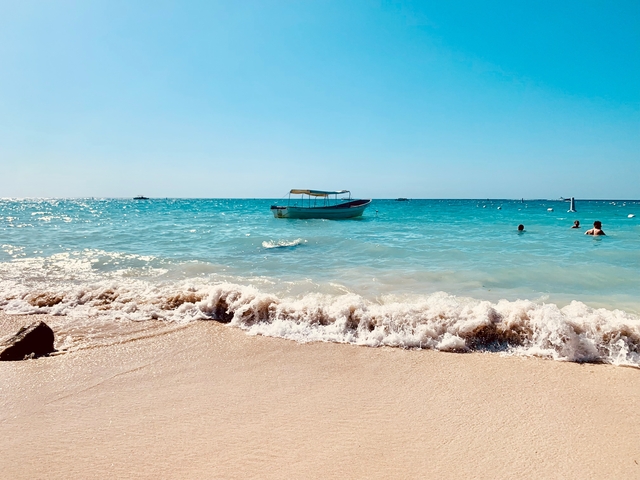 A boat on the sea with people swimming nearby.