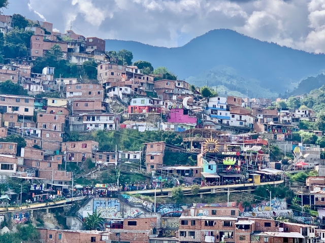 A hillside with colorful houses and a busy street below.