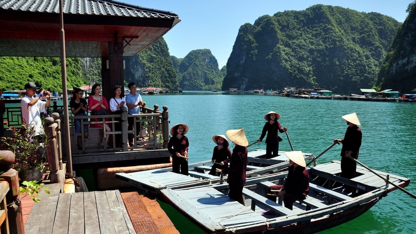 People on wooden boats in a scenic bay.