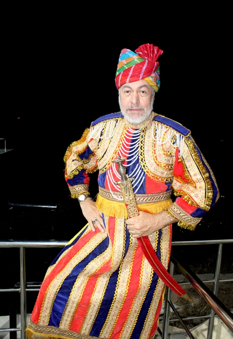      Man wearing traditional attire posing with a sword.
  