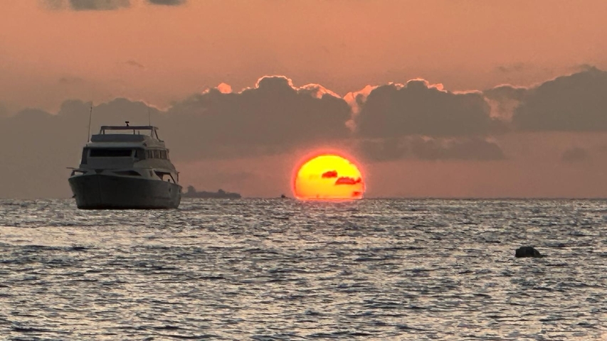 Boat on the ocean with a sunset in the background.