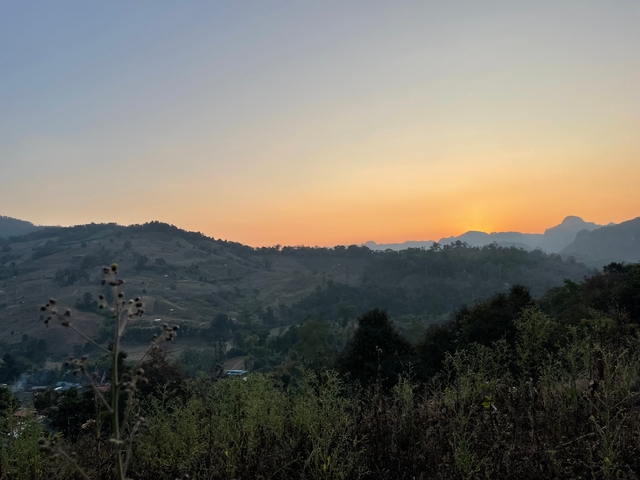 Sun setting over distant mountains with clear sky.