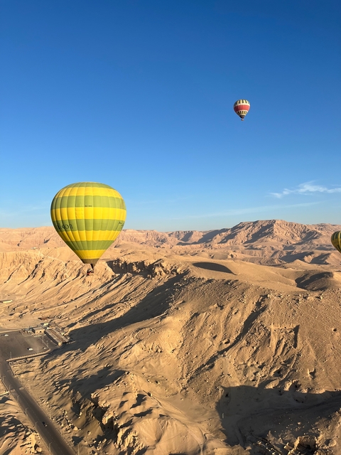 Hot air balloons flying over a desert landscape.