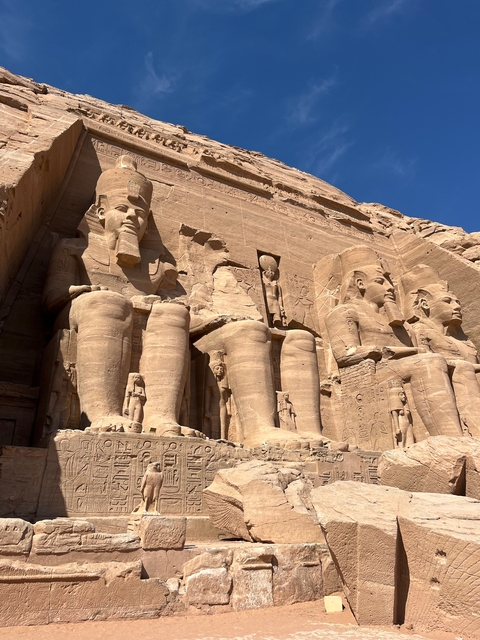 Colossal statues carved into a rock cliff.