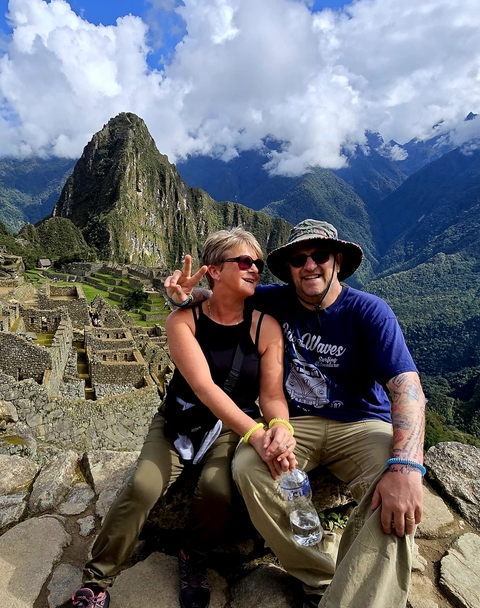 Couple posing at Machu Picchu with mountains in the background.