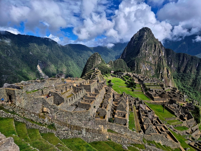 Wide view of Machu Picchu with lush mountains surrounding it.