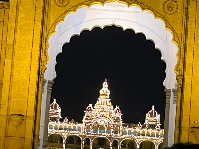       Illuminated palace framed by a decorative arch at night.
  
