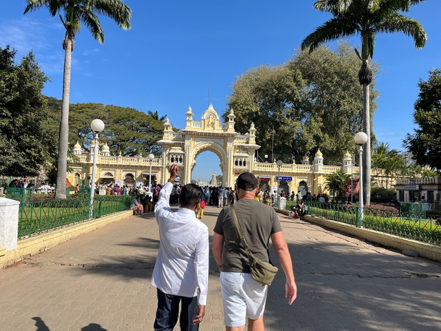       Two people walking towards a grand entrance of a palace with many visitors.
  