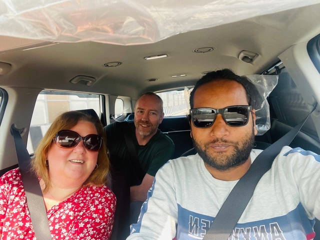       Three people inside a car smiling and taking a selfie.
  