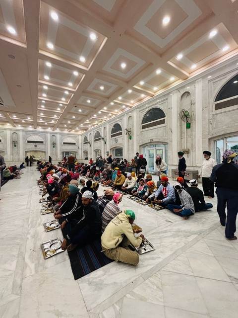       People sitting in a community dining area inside a temple.
  