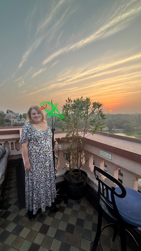       Person standing on a terrace with sunset view.
  