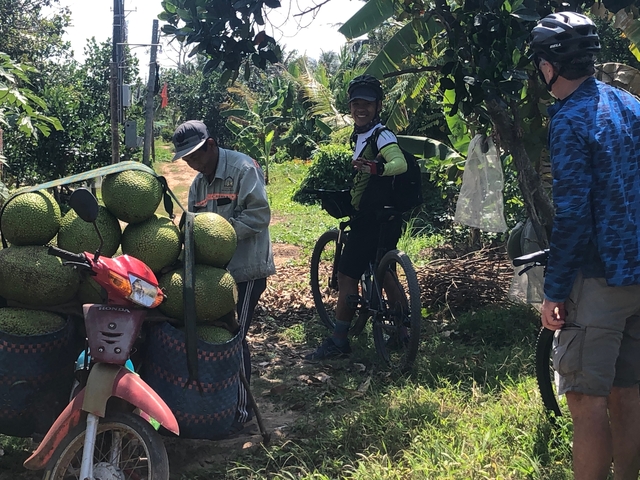 People interacting with locals and produce in a rural area.