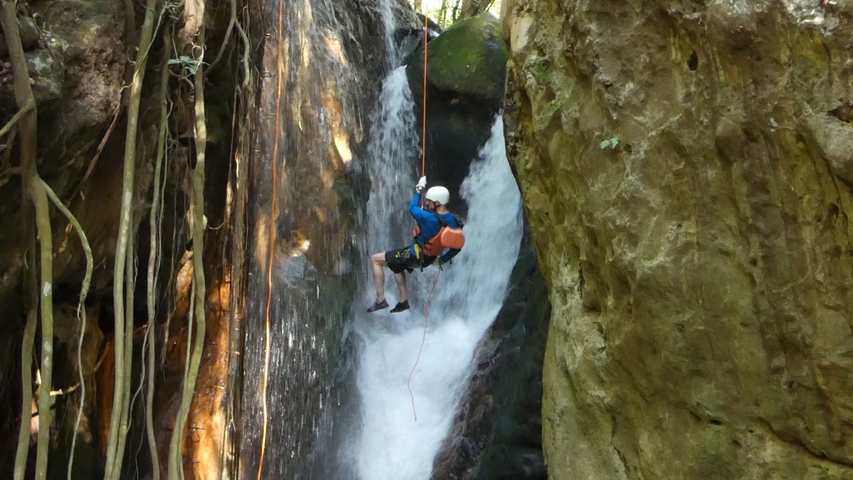       A person rappelling down a waterfall.
  