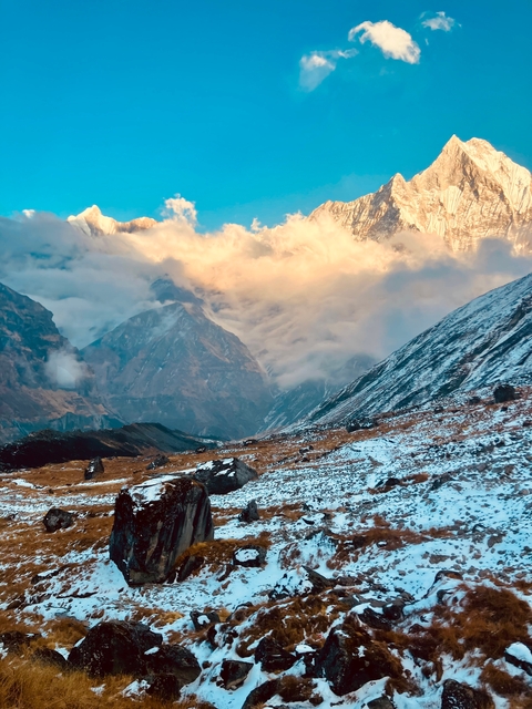 Snowy mountain landscape with clouds and blue sky.