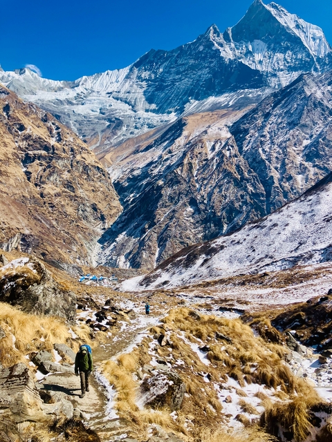 A rugged mountain landscape with snow-covered paths.