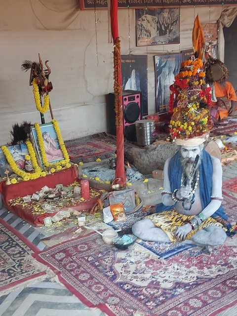       A man with traditional attire in a decorated tent.
  