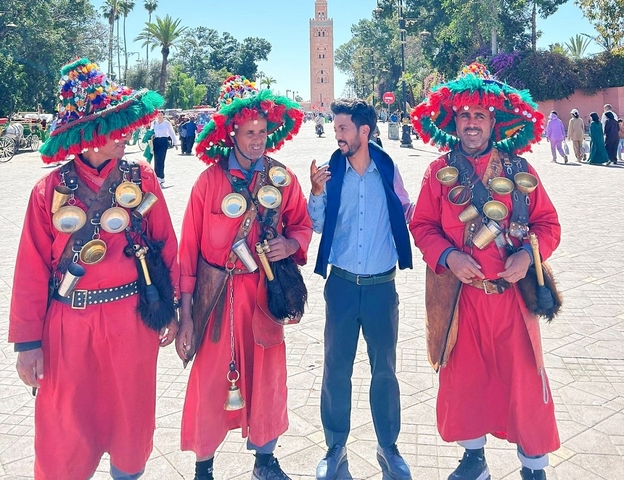 Four men in traditional attire engaged in a conversation.